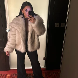 Beige pälsjacka - Säljer en lyxig beige pälsjacka med långärmad design. Jackan har en oversized passform och är perfekt för kyligare säsonger. Den är både stilren och trendig, vilket gör den till ett måste i garderoben.