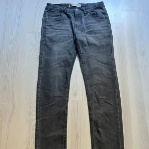 Grå jeans från Levi's - Snygga grå jeans från Levi's med klassisk femficksdesign och knappgylf. Modellen är 512, vilket ger en modern och bekväm passform. Perfekta för en stilren look.