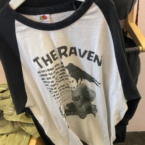 Svartvit lång armad med Edgar Allan Poe tryck  - Cool svartvit lång armad från Fruit of the Loom med tryck av 'The Raven'. Den har svarta ärmar och en vit kropp med ett stort tryck på framsidan. Perfekt för en avslappnad stil.