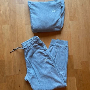 Grå hoodie och byxor från Nike - Grå hoodie och matchande byxor från Nike. Byxorna är något slitna i sömmen enligt sista bilden.