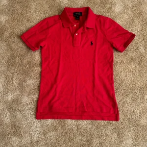 Röd pikétröja från Ralph Lauren - Säljer en klassisk röd pikétröja från Ralph Lauren med korta ärmar och den ikoniska loggan broderad på bröstet. Perfekt för en stilren och avslappnad look. Tröjan har en mjuk krage och knappar framtill. Märke: Ralph Lauren Skick: 9/10 Storlek: S Ord pris: 799  Din stil: spara inlägget så du inte missar denna kappa Inte din stil: Kolla min profil. Du kommer hitta 