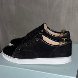 Svarta sneakers från märket Lanvin - Snygga svarta sneakers med vit sula och snörning. Tillverkade i mocka med en stilren design. Perfekta för en avslappnad stil. Skornas nypris är 5200kr. Pris kan diskuteras 👍