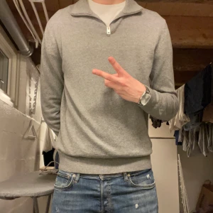 Grå halfzip från Jack & Jones - Säljer en stilren grå tröja från Jack & Jones med dragkedja vid halsen. Perfekt för en avslappnad look. Storlek M