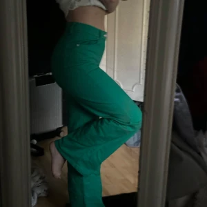 Gröna raka byxor - Säljer ett par gröna byxor med hög midja och raka ben. Byxorna har klassisk femficksdesign och stängs med knapp och dragkedja. Perfekta för dig som vill ha en färgklick i garderoben!