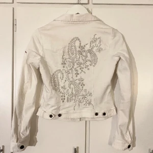 Vit jeansjacka med broderi från Odd Molly - Säljer en vit jeansjacka från Odd Molly med snyggt broderat mönster i på ryggen och insidan. Jackan har knappar framtill, två bröstfickor och lång ärm. Jackan är i storlek XS
