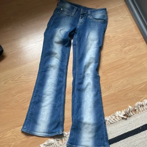 Kvarg  jeans från Cheap Monday - Säljer ett par blå bootcut jeans från Cheap Monday med klassisk femficksdesign och knappgylf. Jeansen har en snygg tvätt med ljusare partier framtill och är perfekta för dig som gillar en retrostil.
