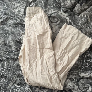 Beiga linnebyxor från Gina Tricot - Säljer ett par beiga linnebyxor från Gina Tricot i storlek XS. Byxorna har resår i midjan och är raka i modellen, perfekta för en avslappnad stil. Lätta och luftiga, passar bra till varmare dagar.