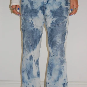 Blåvit batikmönstrade jeansbyxor - Unika blå och vita jeansbyxor med batikmönster och markerade sömmar. Byxorna är utsvängda och låg midja🥰det står strl 40 men skulle säga att de mer är en strl 36-38