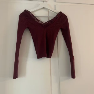 Vinröd ribbad topp med spets från H&M Divided - Vinröd långärmad topp från H&M Divided med ribbad struktur och v-ringning dekorerad med spets. Snygg och feminin modell som passar perfekt till många olika outfits.