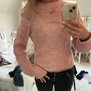 Rosa stickad tröja med mönster - Mysig rosa stickad tröja. Tröjan har ett diskret hålmönster och är något croppad i modellen. Perfekt för lager-på-lager och passar till både jeans och kjol.