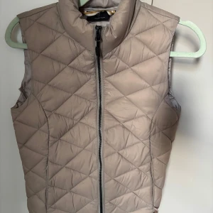 Beige dunväst från JH Collection - Säljer denna fina, quiltade dunväst från JH Collection. Den är i storlek XS och har endast varit använd ett fåtal gånger!🤍