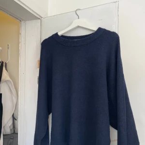Mörkblå stickad tröja från Nelly - Mysig mörkblå stickad tröja från Nelly med rund halsringning och långa ärmar. Perfekt för kyligare dagar och enkel att matcha med olika outfits.