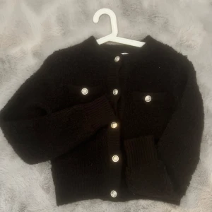 Svart kofta/tröja - Man kan bära plagget både som kofta och tröja. Endast använd en gång därav inga defekter. Köpt för 500 säljer för 300kr men pris kan diskuteras☺️ (tredje bilden är samma plagg fast i krämvit)