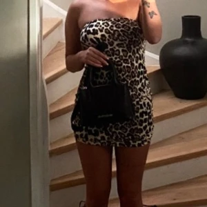 Leopardmönstrad axelbandslös kortklänning - Säljer en snygg axelbandslös kortklänning med leopardmönster. Klänningen har en tight passform och är perfekt för dig som vill sticka ut. Materialet känns mjukt och följsamt mot kroppen.