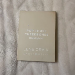  Highlighter - En skimrande highlighter i en varm, champagneguldig nyans. Kommer i en stilren, ljusbeige förpackning med marmorerad ram runt produkten. Perfekt för att framhäva kindbenen med en glowig finish.