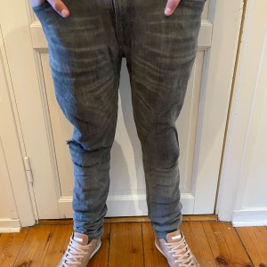 Grå jeans från Nudie  - Säljer ett par grå jeans från Nudie Jeansco med normal passform och klassisk femficksdesign. Jeansen har en diskret tvättad look och är tillverkade i denim. Perfekta för dig som gillar stilrena och bekväma jeans.