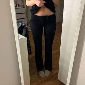 Lågmidjade kostymbyxor - Säljer ett par svarta bootcut kostymbyxor med låg midja och två knappar framtill. De är aldrig använda bara testade och därav lappen kvar☺️
