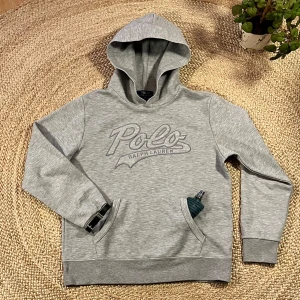 Grå hoodie från Polo Ralph Lauren - Snygg grå hoodie från Polo Ralph Lauren med broderad logga framtill. Tröjan har huva och en stor magficka. Perfekt för en sen sommarkväll. Pris kan diskuteras! Passar bäst som 170-176💯