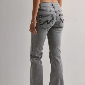 Nelly jeans - Säljer ett par grå bootcut jeans med svarta sömmar och markerade bakfickor. Jeansen har normal passform och klassisk femficksdesign. Säljer även samma i mörkblått .