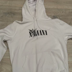 Vit Nirvana hoodie - Säljer en vit Nirvana hoodie, I jättebra skick förutom en väldigt liten blåprick, som kanske går bort har ej testat. Den är väldigt fin och perfekt för dig som gillar Nirvana. Det står XL men kan funka om du har lite mindre storlek.