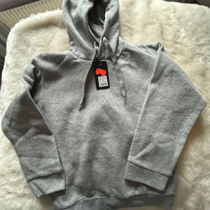 Grå hoodie med mjuk insida - Säljer en klassisk grå barn hoodie från FUZE. Den är markerad som storleken 146-152, men de är väldigt liten i storleken. Skulle säga att den passar 122-128.Tröjan har huva med dragsko, ribbade muddar och en riktigt mjuk, fleecefodrad insida. Perfekt för en avslappnad och stilren look. Den är helt ny och har inga tecken på användning, endast provad. Säljer även en likadan i svart, så gå in på min profil om du är intresserad!😊😊 Säg till om du har några frågor! 
