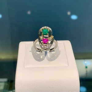 Silverfärgade örhängen med gröna och rosa stenar - Unika örhängen i silverfärg med en oval form, prydda med en grön och en rosa sten samt små gnistrande stenar runtom. Perfekta för dig som vill sticka ut med färg och elegans.