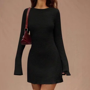 Svart långärmad kortklänning med öppen rygg - Säljer en svart, figurnära kortklänning med lång ärm och lätt struktur i tyget. Klänningen har en snygg öppen rygg med knytband upptill. Perfekt för dig som gillar stilrena och trendiga plagg. Från SHEIN. Aldrig använd då jag provade den men klänningen var för liten. Så finns med prislapp och allt. 