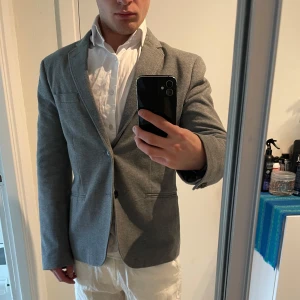 Kavaj H&M 44 - Grå kavaj med en knappstängning och klassisk krage. Perfekt för en avslappnad men ändå stilfull look. Från H&M. Mycket bra skick.