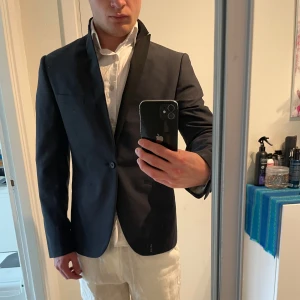 Svart kavaj från Emilio - Svart kavaj från Emilio Denim Issue. Kavajen har en slim fit passform och stängs med en knapp. Extra knappar medföljer. Storlek 92E, sitter som XS