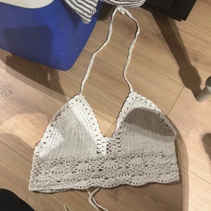 Vit virkad croppad linnetopp - Säljer en handvirkad vit linnetopp med knytning i ryggen. Toppen är ärmlös och har en bohemisk känsla med fina virkade detaljer. Perfekt för sommaren och festivaler.