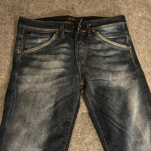 Mörkblå slim fit jeans från Jack & Jones - Säljer ett par mörkblå jeans från Jack & Jones, modell Glenn Slim Fit. Har växt ur dom så det är inget fel på byxorna, bara lite små i storleken.