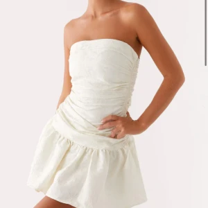 Superfin volangklänning - Superfin vit klänning med kort volangkjol. Klänningen har snörning i ryggen och jättefint tyg! Helt ny och aldrig använd!