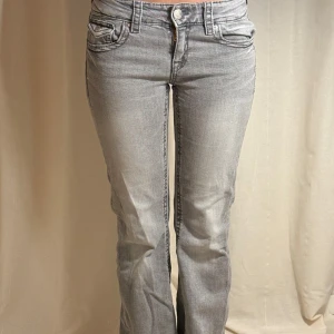 Jeans från Gina Tricot  - Säljer ett par grå jeans med bootcut passform och snygga fickdetaljer med knappar både fram och bak. Jeansen har låg midja och klassisk femficksdesign. Jeans passar mig som är XS/S.Pris kan diskuteras🩷