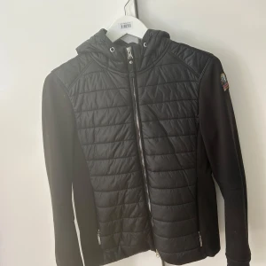 Svart fleece och pufferjacka från Parajumpers - Säljer en svart jacka från Parajumpers i storlek S. Jackan kombinerar fleece och pufferdesign med dragkedja framtill samt två dragkedjor längst ryggen. Jackan har även två fickor fram med dragkedja samt två innerfickor. Jackan är sparsamt använd och köpt på Thernlunds. Kvitto och tags finns.