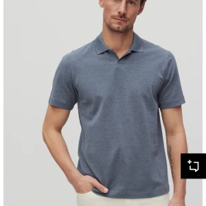 Blå pikétröja från Bläck - Säljer en stilren blå pikétröja från Bläck. Tröjan har korta ärmar och en klassisk krage. Perfekt för en avslappnad look. Passar bra till både jeans och chinos.