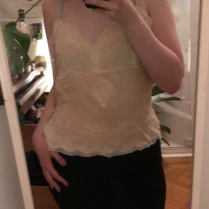 Beige spetslinne från Jennyfer - Säljer ett romantiskt beige spetslinne från Jennyfer. Linnet har tunna axelband och vackra broderade blommor i vitt. Perfekt för en somrig look eller som ett lager under en kavaj. 💫