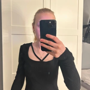 Svart ribbad topp från Chiquelle - Säljer en stilren svart ribbad topp från Chiquelle i storlek XS. Toppen har en unik design med smala band över bröstet och långa ärmar. Perfekt för en trendig look!💞