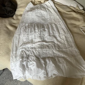 Vit lång kjol med blommönster  - Fin lång kjol köpt på marknad! Står ingen storlek med uppskattar att den är som S men stretchig i midjan! Oanvänd