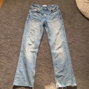 Blå jeans från Zara - Säljer ett par snygga blå jeans från Zara i storlek XS. De har en klassisk femficksdesign och en fransig nederkant för en trendig look. Perfekta för en avslappnad stil.