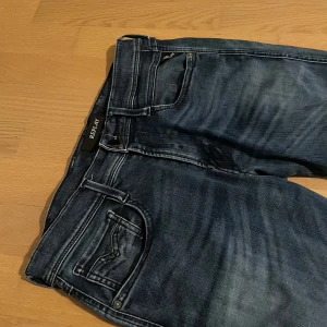 Mörkblå replay anbass jeans - Snygga mörkblå jeans från Replay med en klassisk femficksdesign. Jeansen har en lätt tvättad look och dragkedja i gylfen. Perfekta för en avslappnad stil.