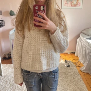 Vit stickad tröja - Säljer en mysig vit stickad tröja med lång ärm. Perfekt för kyligare dagar och ger en avslappnad look. Tröjan har en fin struktur och är lätt att matcha med olika outfits.
