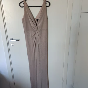 Balklänning  - Helt oanvänd balklänning med prislappen kvar. Champange färgad med glitter. Din detalj framtill och även en slits. 