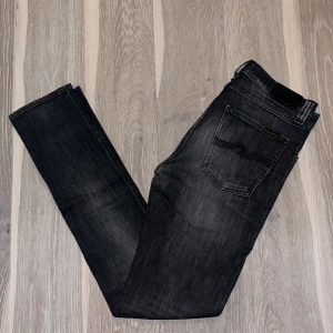 Nudie Jeans - Snygga svarta Nudie Jeans i storlek 30/32, men sitter mer som 29/32. Nypris: 1500, mitt pris: 225. Skicket är bra förutom en defekt på jeansen som man ser på den fjärde bilden. De har en tvättad look och är perfekta för en stilren vardagsoutfit. Modellen är slim fit.