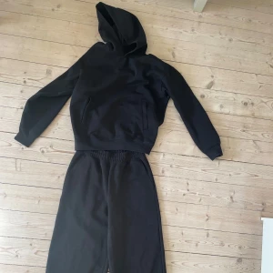 Svart sweat set från Uniqlo - Säljer ett stilrent svart sweat set från Uniqlo. Det finns att hitta på uniqlo's hemsida i "Uniqlo: C" kollektionen, tröjan heter "Sweat oversized pullover hoodie" och byxorna "Wide sweatpants" Tillsammans kostade det 900kr men jag säljer för halva priset! säljer för jag vill köpa ett nytt mjukis set i annan färg  dessa är precis som nya, inga fläckar eller skador på plaggen.  hoodie Storlek Extra small och byxor i Small. hör av dig för mått eller frågor gällande storleken!