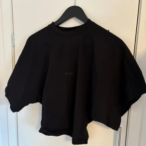 Svart topp från AVORA - Snygg svart topp från AVORA med en enkel och stilren design. Den sitter tight i midjan och korta lösa ärmar. Nypris 800kr
