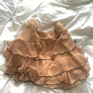 Ljusrosa volangkjol från Zara - Säljer en söt ljusrosa kjol från Zara med flera lager av volanger och svarta kanter. 
