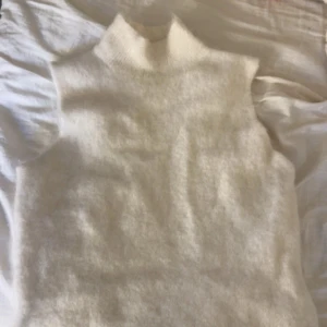 Vit stickad topp från Stockh LM Studio - Säljer en stilren vit stickad topp från Stockh LM Studio. Toppen har en hög krage och är ärmlös. Skriv för fler bilder, skicka gärna pris förslag. Storlek M men sitter som S.