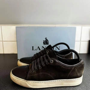 Bruna Lanvin - Säljer ett par sjukt fräscha och snygga lanvin i storlek 41. Skorna är i en mörkbrun färg så de håller sig bra från smuts. Skicket är ok men lite smuts runt sulorna! Skriv för mer info!🤩 (Box ingår)