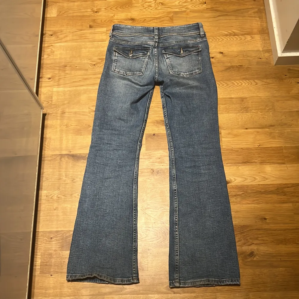 Säljer ett par klassiska blå bootcut jeans från Gina Tricot i storlek 158. Jeansen har fem fickor, dragkedja och knapp framtill samt snyggt utsvängda ben. Perfekta för dig som gillar en tidlös denimlook.. Farkut & Housut.