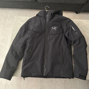 Arc'teryx Macai LT jacka - Säljer en svart jacka från Arc'teryx som är modellen Macai LT. Jackan har flera praktiska fickor med dragkedjor och en stilren design. Perfekt för kyligare väder och aktiviteter som skidor. Storlek S, men sitter som en M. Den är knappt använd så är nästan i nyskick. Nypris 8499kr